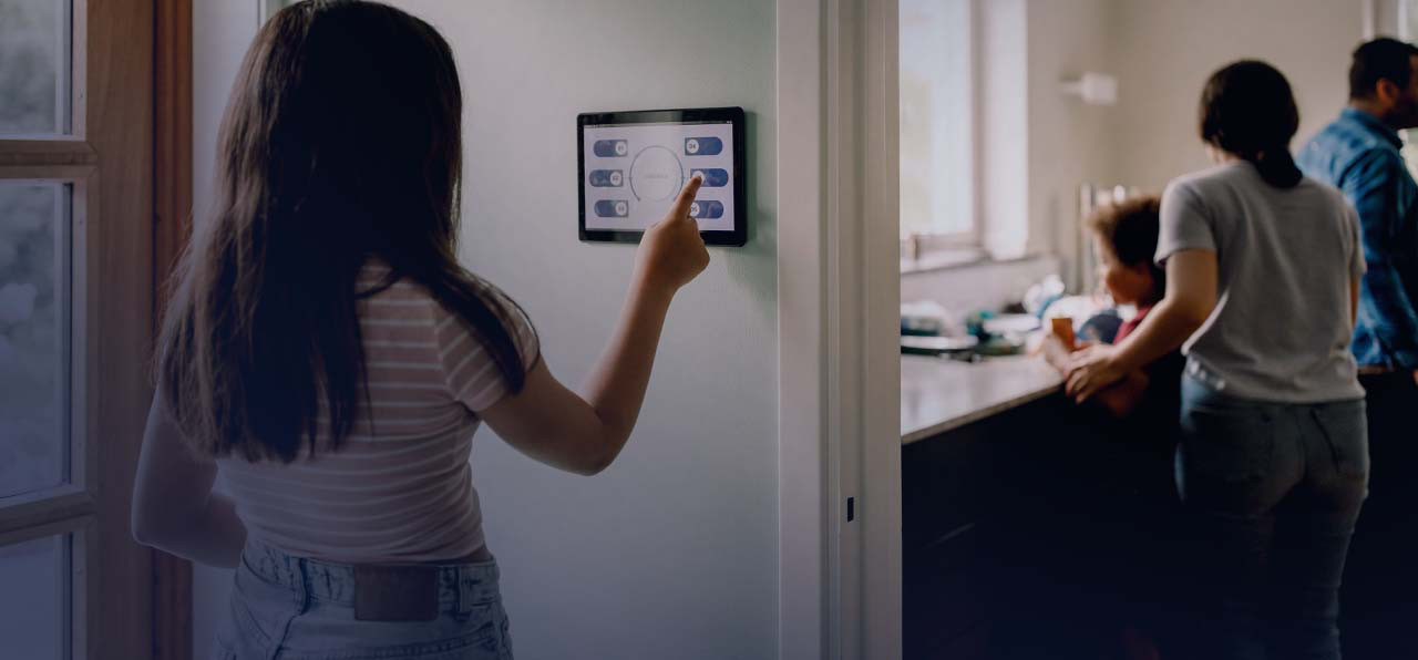 A women is touching the screen of tablet attached to the wall.