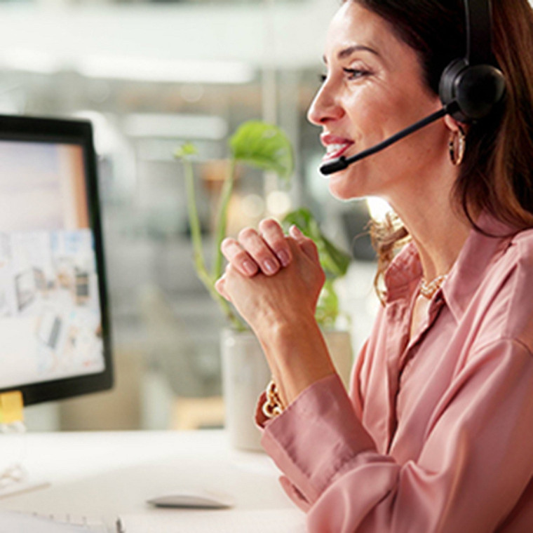 A woman on her headphone set looking at her monitor screen.
