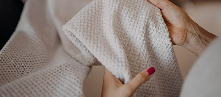 A human hand holding a white textured cloth