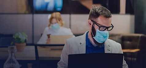 masked employees work on laptop