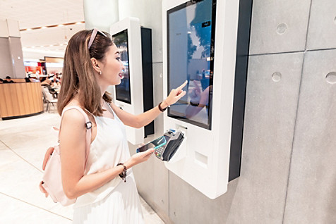 the girl makes an order in a fast food restaurant at the self-service terminal in the mall.