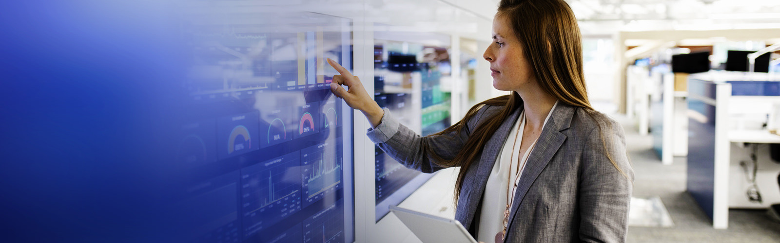 Woman using a wall-mounted screen displaying graphs and charts