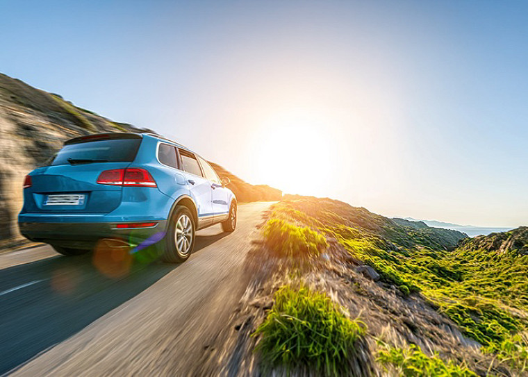A car driving on a hill towards uphill where the sun is shining