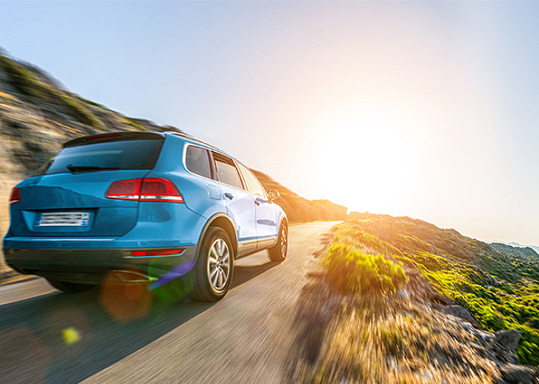 A car driving on a hill towards uphill where the sun is shining