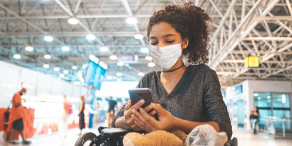 Frau mit Maske schaut aufs Telefon