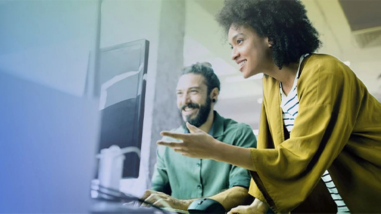 Two colleagues looking at a computer scree, smiling and discussing something