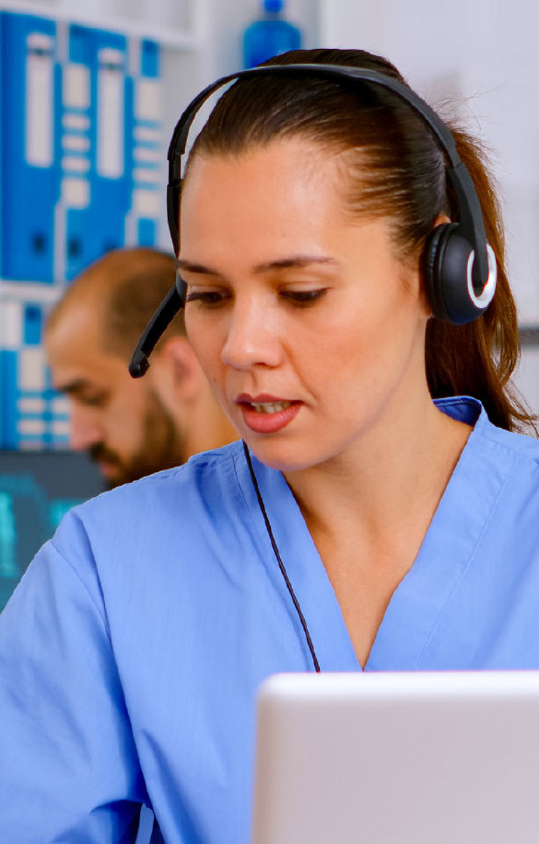 A healthcare professional taking a client call using her headphone