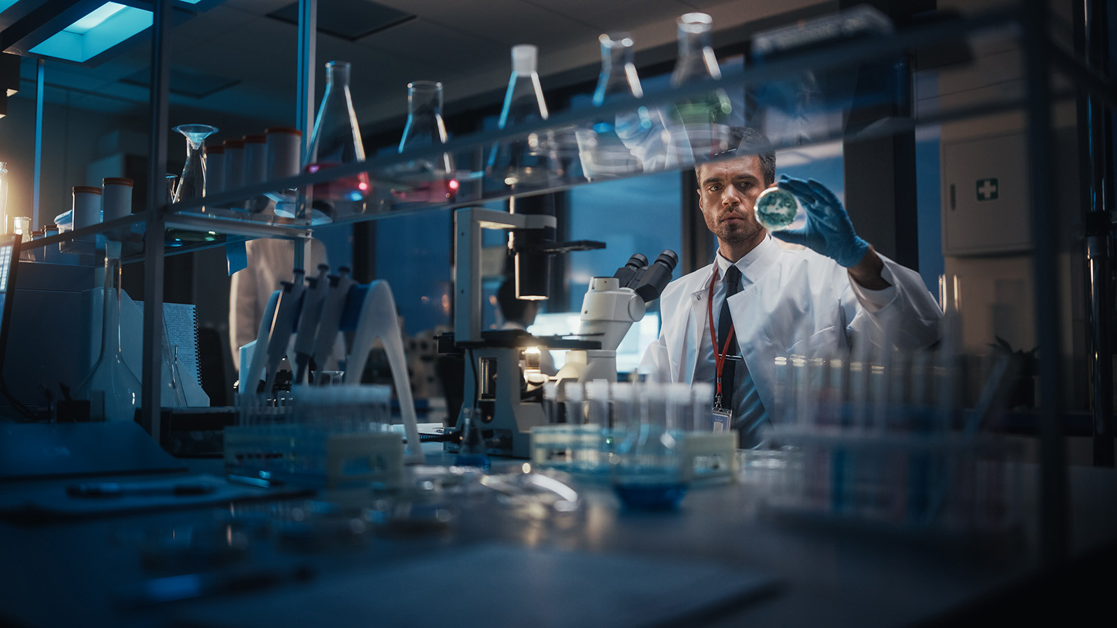 Man working in lab, looking at globe like object thinking of taking over the world