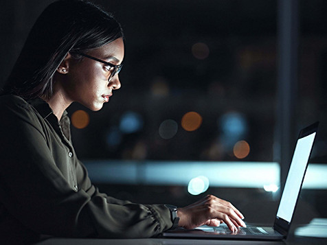 Frau mit Brille, die konzentriert an einem Laptop arbeitet