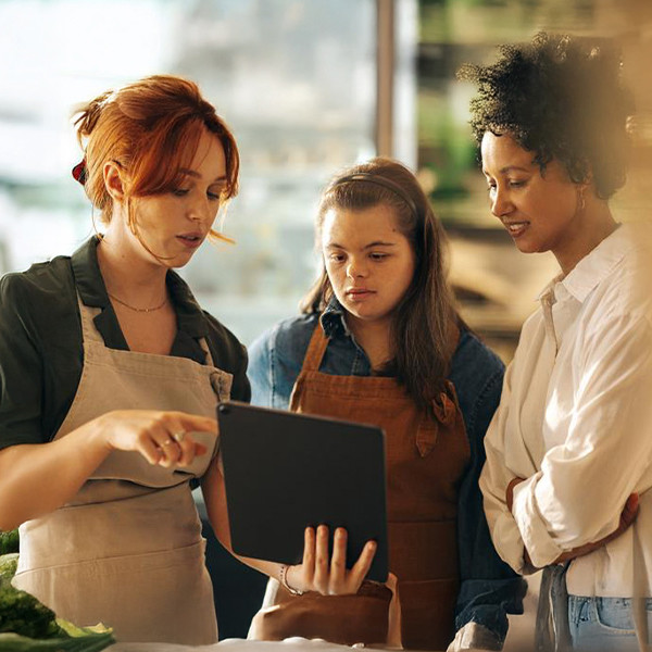 A store worker showing something on a tablet to two colleagues