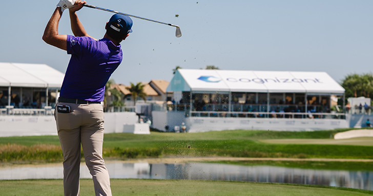 A male golfer in mid stride of hitting golf ball.