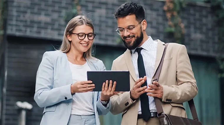 Two professionals reviewing information on a tablet outdoors