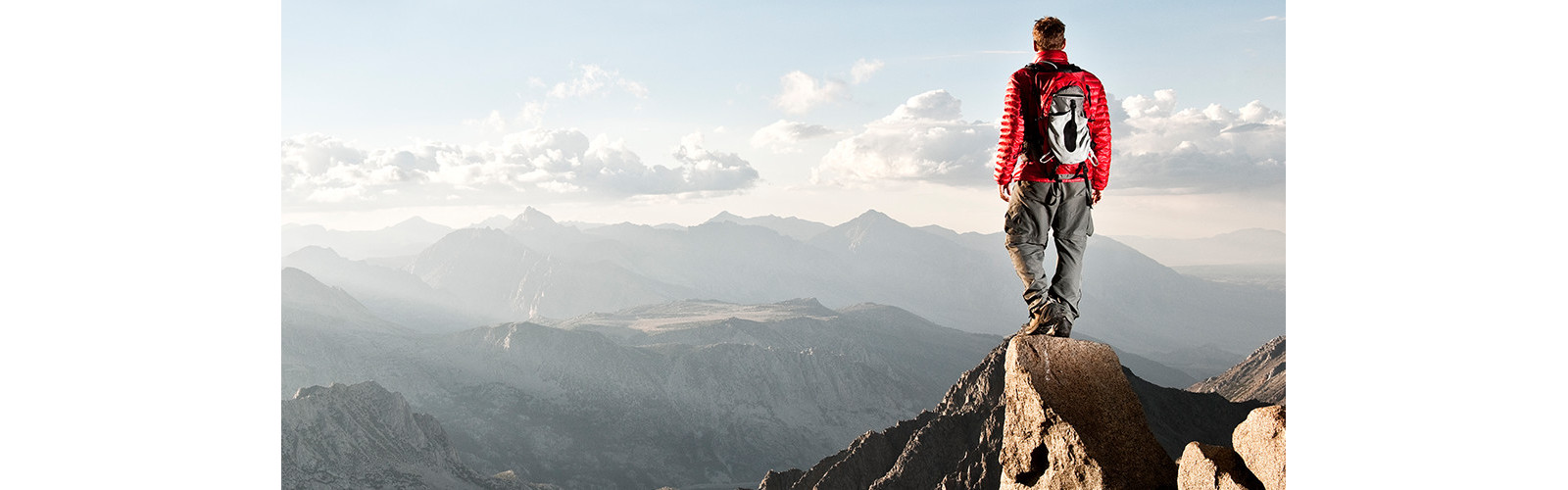 A man standing on top of a mountain peak