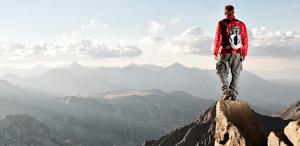 A man standing on top of a mountain peak
