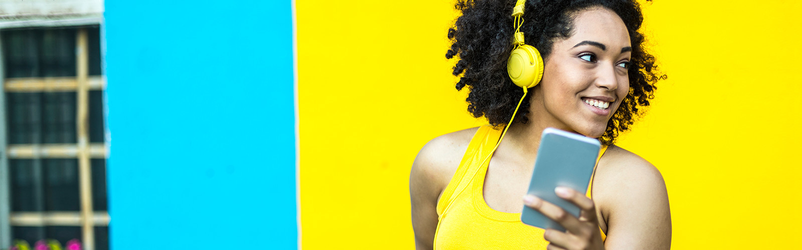 Woman smiling looking sideways while listening to something on headphones