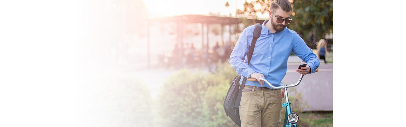 A man walking with a bicycle while watching something on his phone