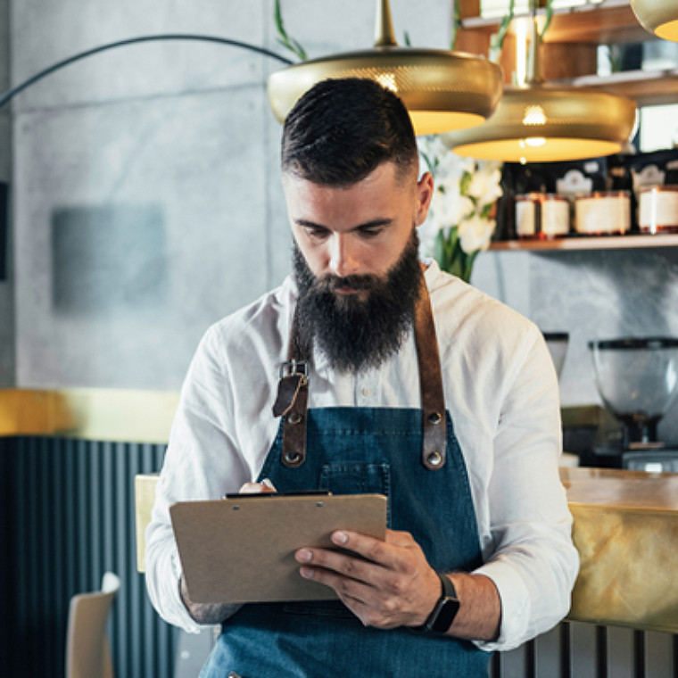 A male employee writing on his clipboard.