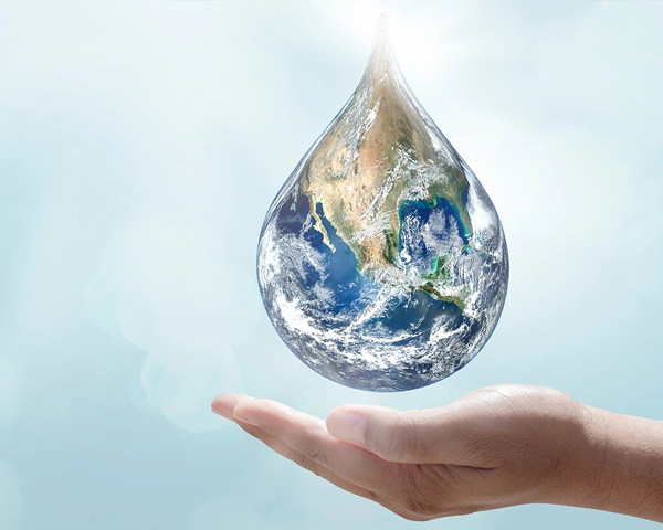 Abstract image of a hand and a droplet with Earth image inside it