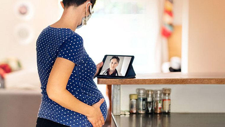 Gravid kvinne på telefonen ved hjelp av et nettbrett