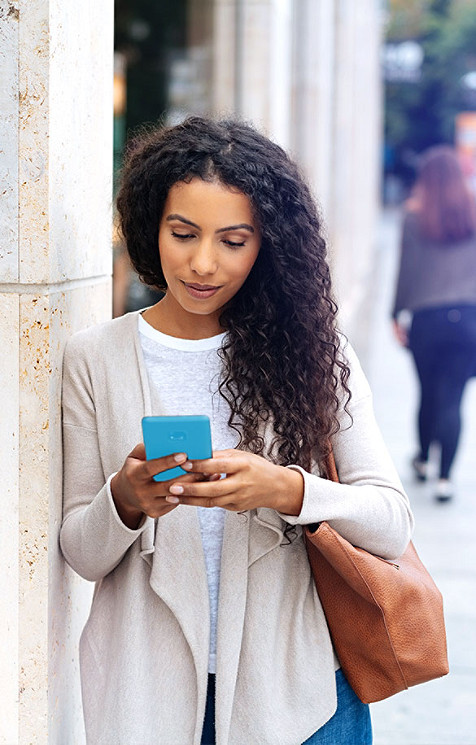 Mädchen überprüft ihr Handy, das neben einer Säule steht