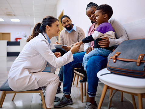 A medical professional attending to a child perched on his mother's lap