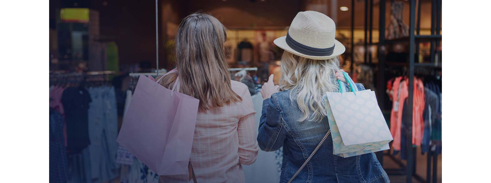 Two woman are holding bags with the hands in a shop.