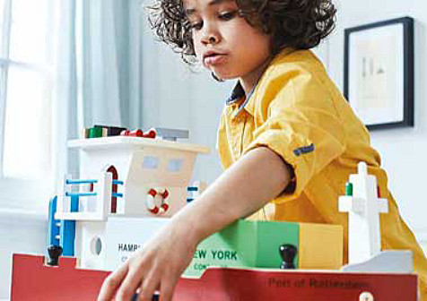 A child is playing with a model of a ship