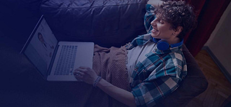 A lazy guy sitting on a couch and enjoying some entertainment on his laptop