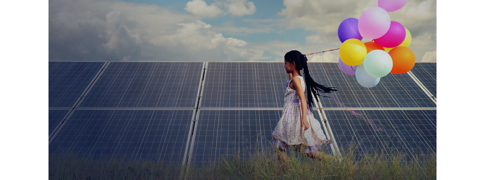 a girl running with balloons beside a solar panel