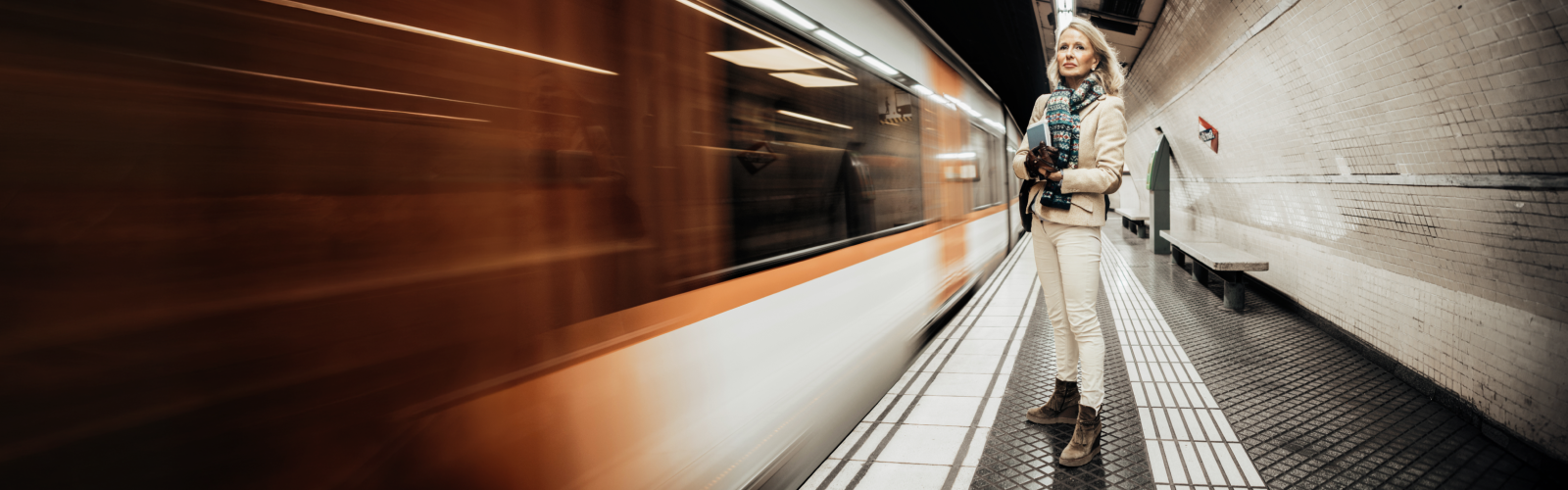 Woman standing on subway platform as train speeds past