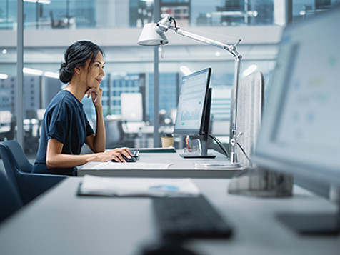 Frau arbeitet an einem Desktop-Computer in einer Büro­umgebung