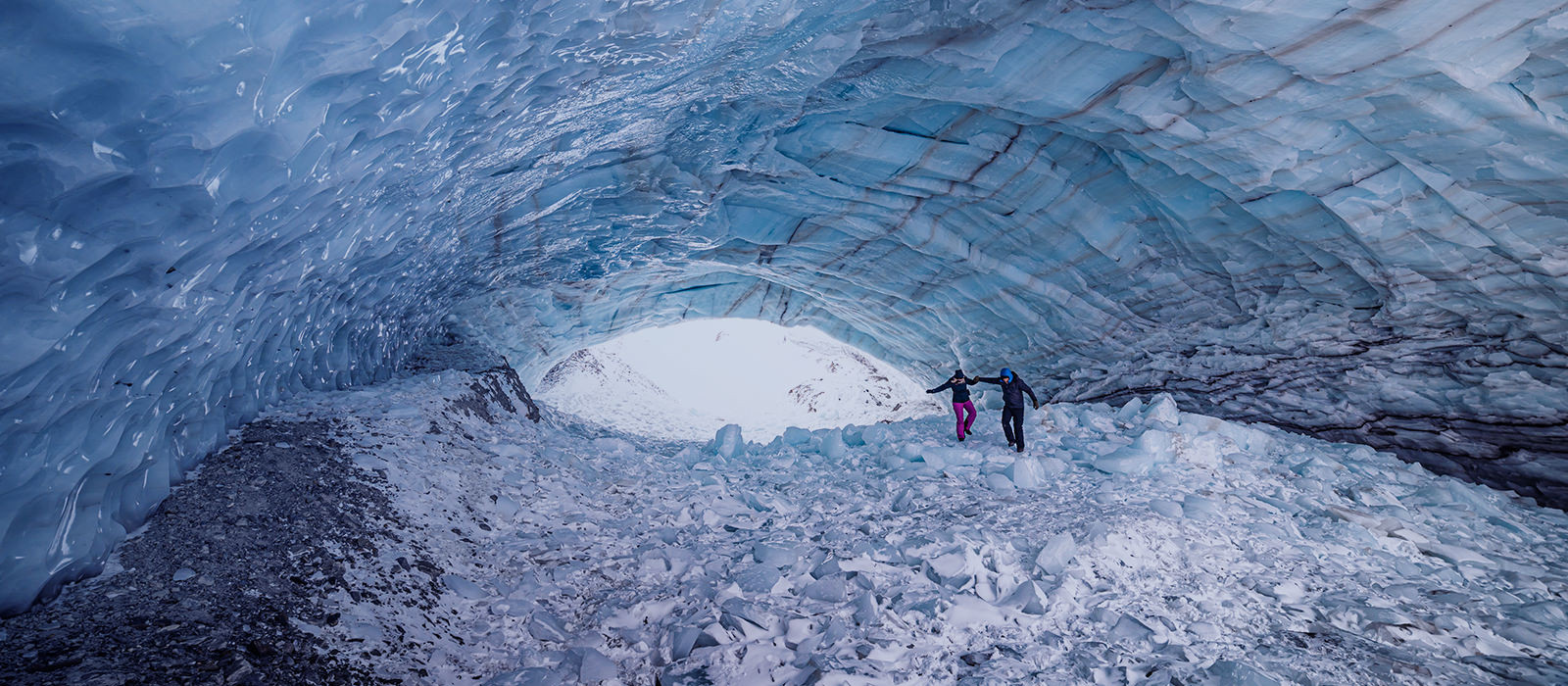 A couple walking inside a cave filled with ice