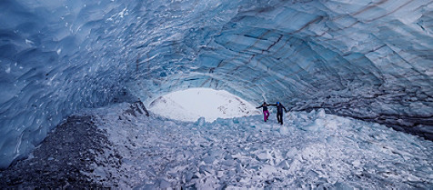 A couple walking inside a cave filled with ice