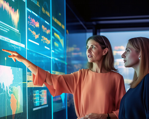 Woman pointing at a screen and speaking with other woman