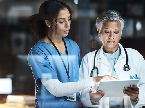 Two medical professionals standing and studying content on a tablet