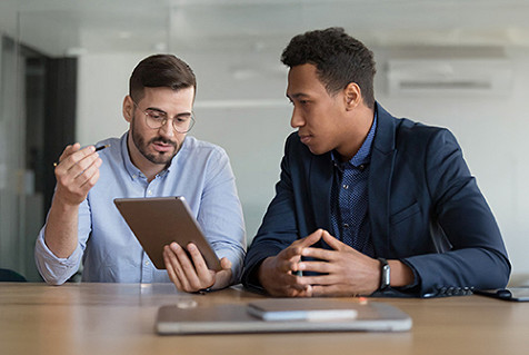 Two professionals reviewing a tablet