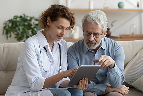 Healthcare professional assisting an older adult with a tablet