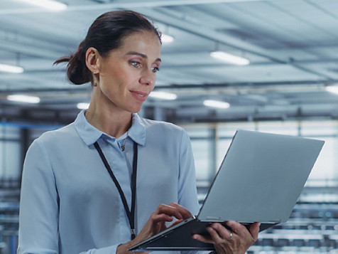 A lady at office holding an open laptop at her hand and checking something