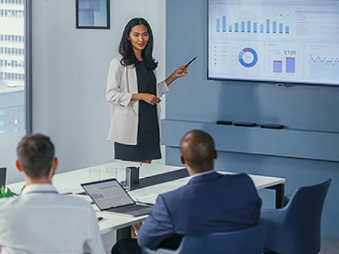 woman looking at a screen and explaining graphs to a team