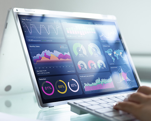 A pair of hands hovering over a keyboard, with the screen displaying various graphs