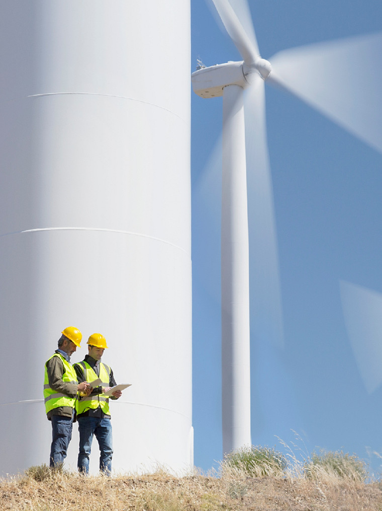 dos trabajadores de pie junto a turbina de viento