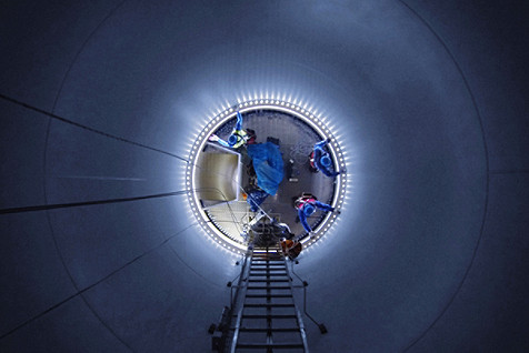 Low Angle View Of Workers In Illuminated Wind Turbine At Night