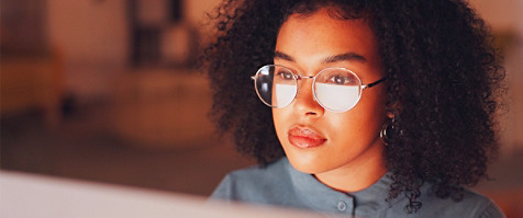 person looking at a screen with the reflection on her spectacles