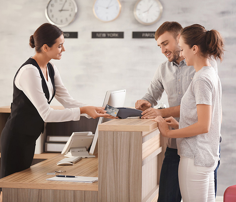 A woman at a helpdesk explaining something to a couple standing on the other side of the desk
