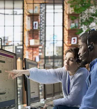 A man and a woman seated at a desk and studying a computer screen display