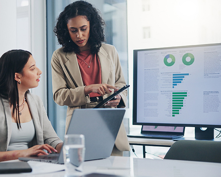 Two woman discussing by focusing on phone in office desk.