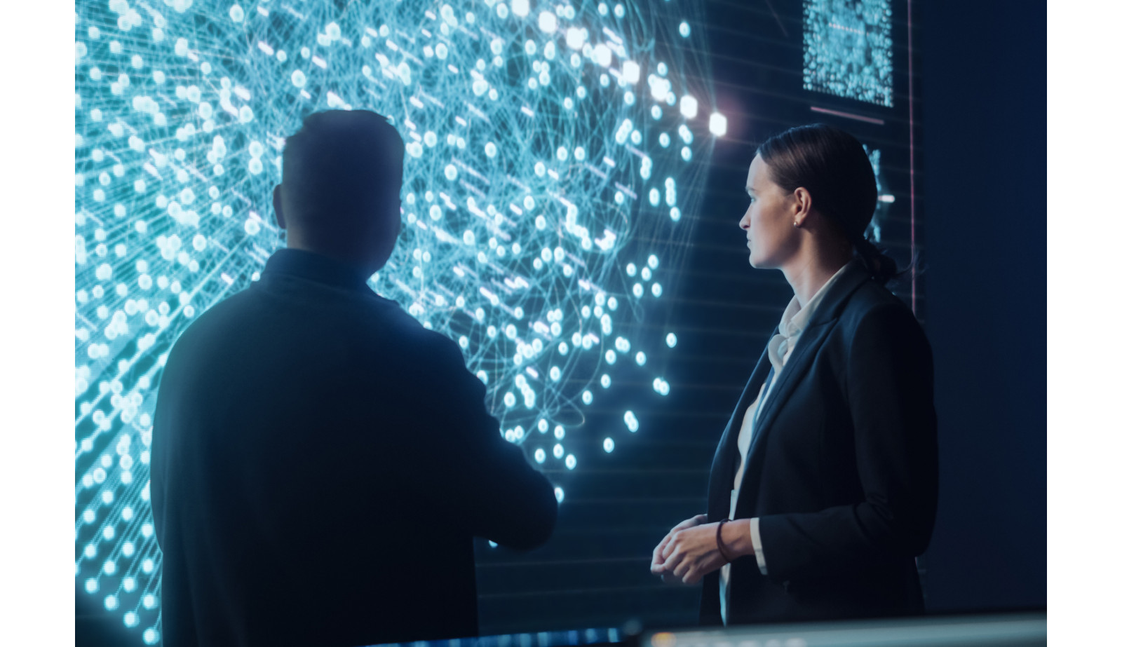 A man and a woman in suits looking at a futuristic visual