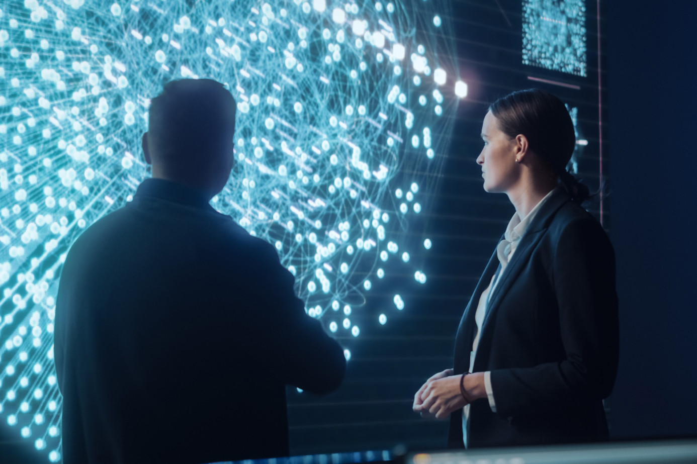 A man and a woman in suits looking at a futuristic visual